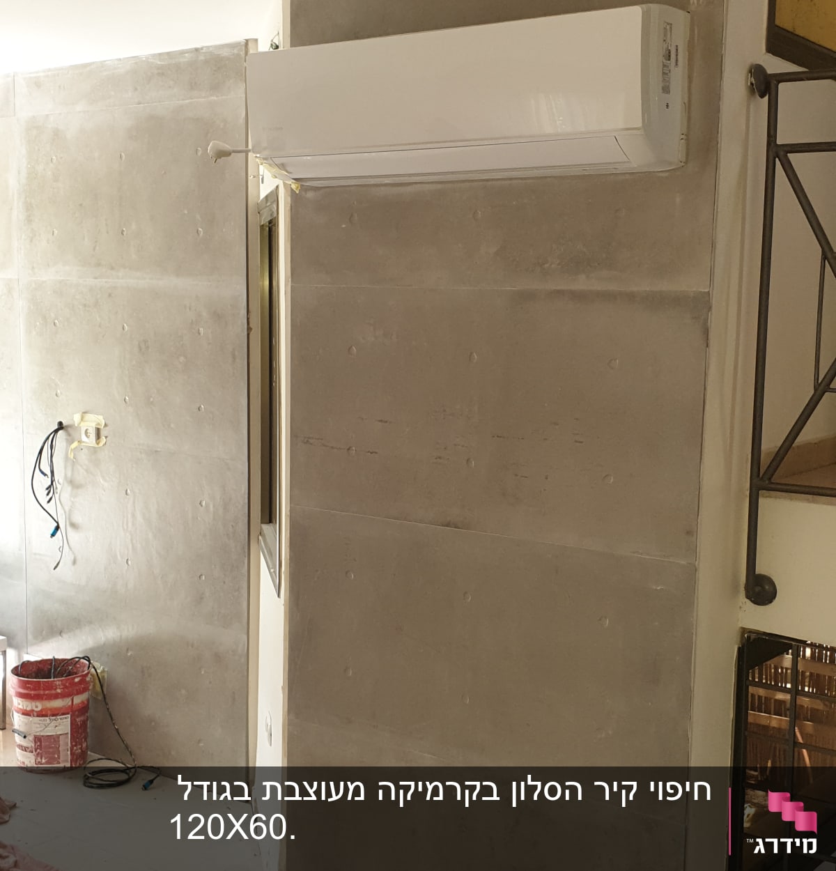 קיר בטון עם מזגן מותקן ודלי צבע על הרצפה